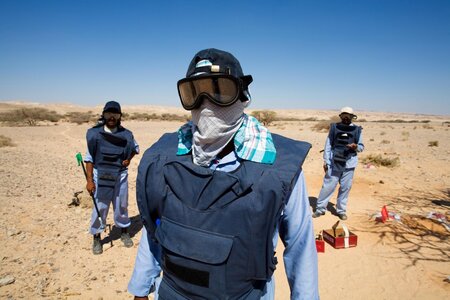 Masked man with soldiers in the desert.